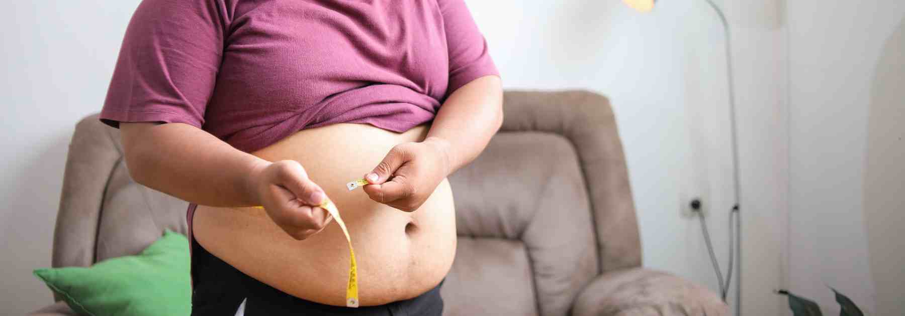 Man measuring weight loss progress with a tape